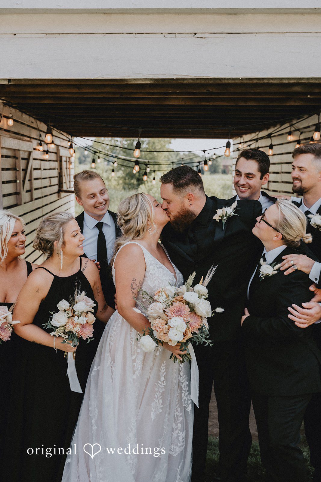 Samantha + Peyton Bride and groom kissing while surrounded by cheering bridesmaids and groomsmen.