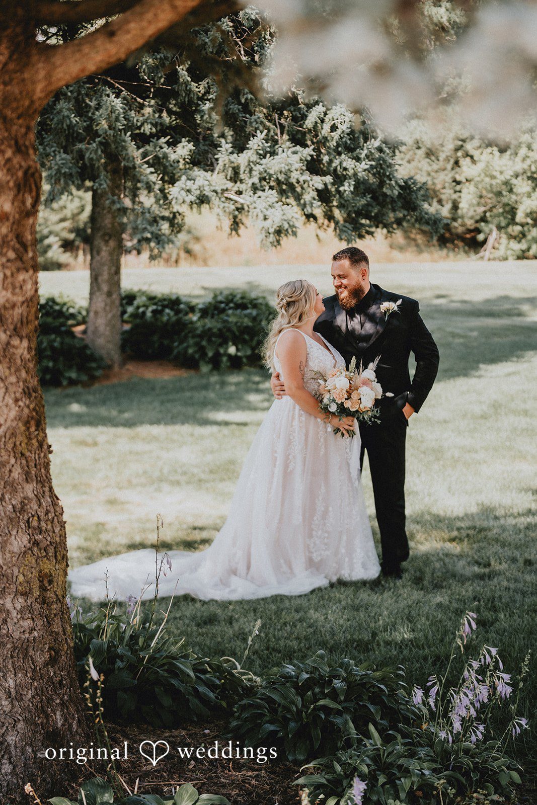 Samantha + Peyton Groom embracing the bride from behind near a tree trunk.