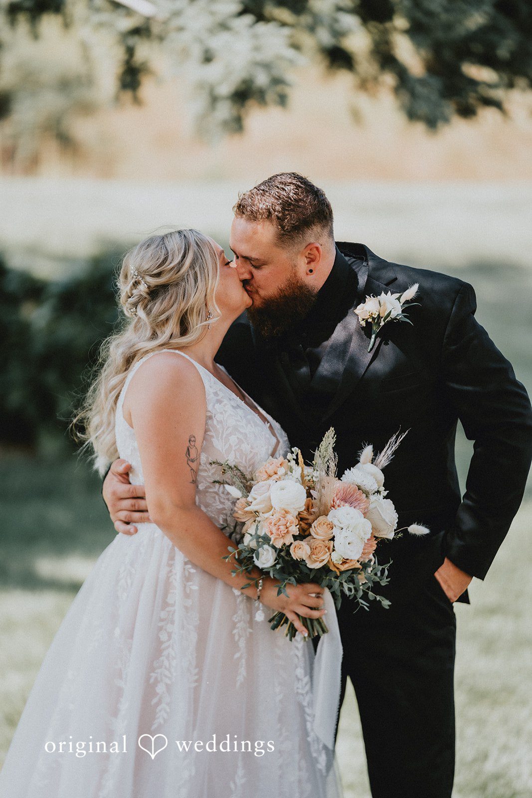 Samantha + Peyton Groom kissing the bride while holding a bouquet.