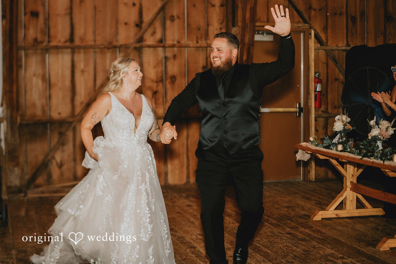Samantha + Peyton Bride and groom holding hands while entering a wooden barn reception.