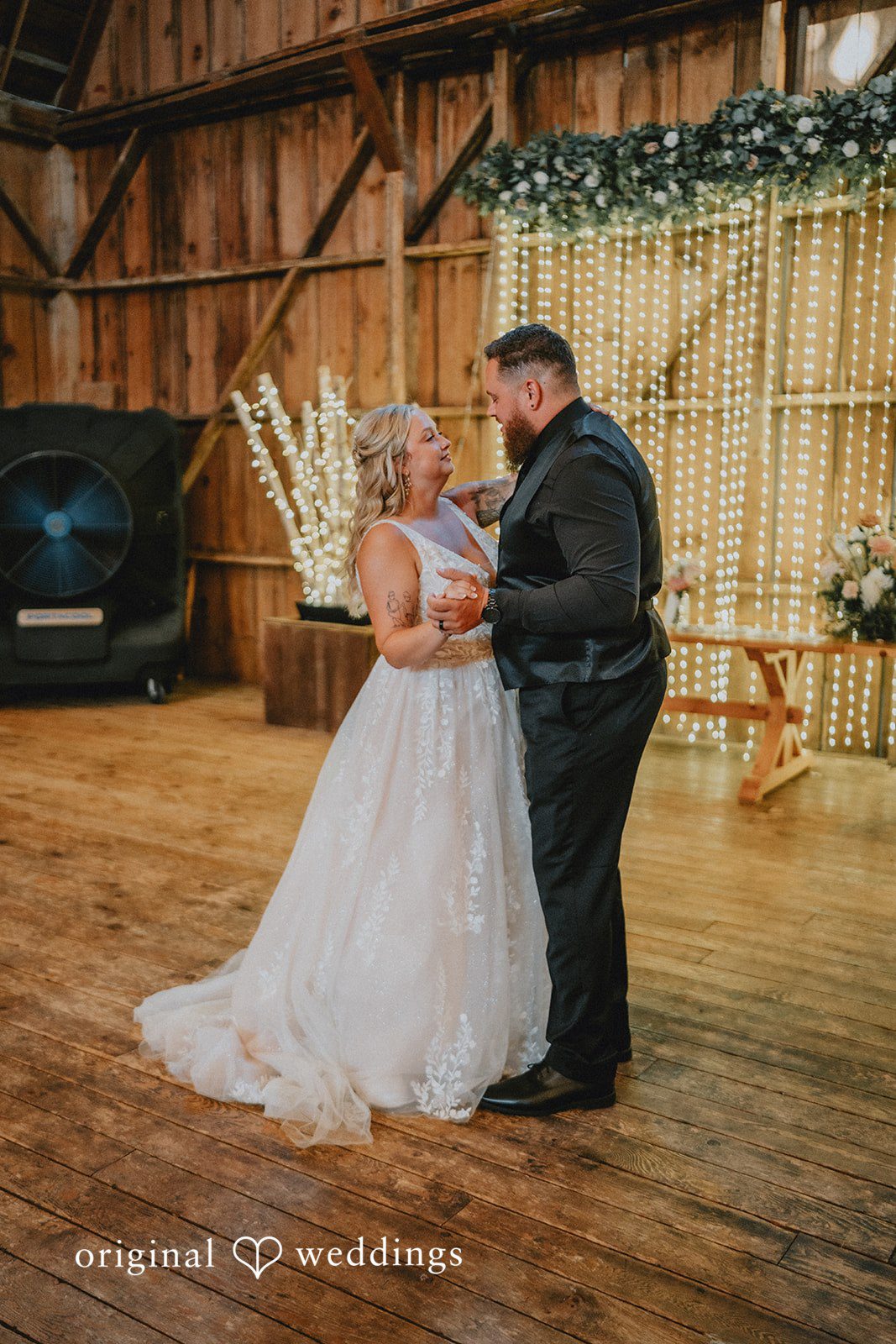 Samantha + Peyton Newlyweds sharing their first dance on a spacious wooden floor.