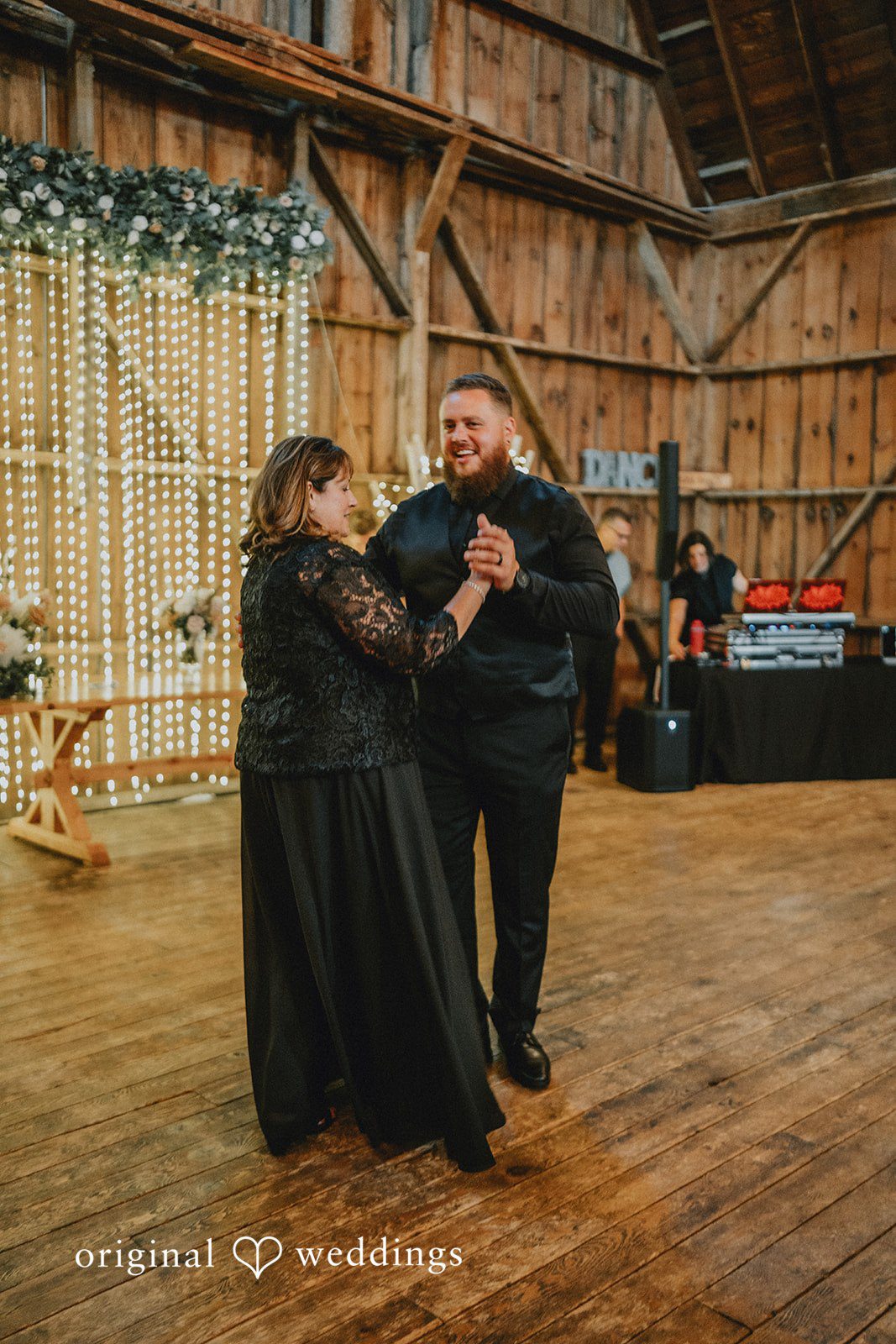 Samantha + Peyton Groom and wedding guests dancing together during a rustic barn reception.