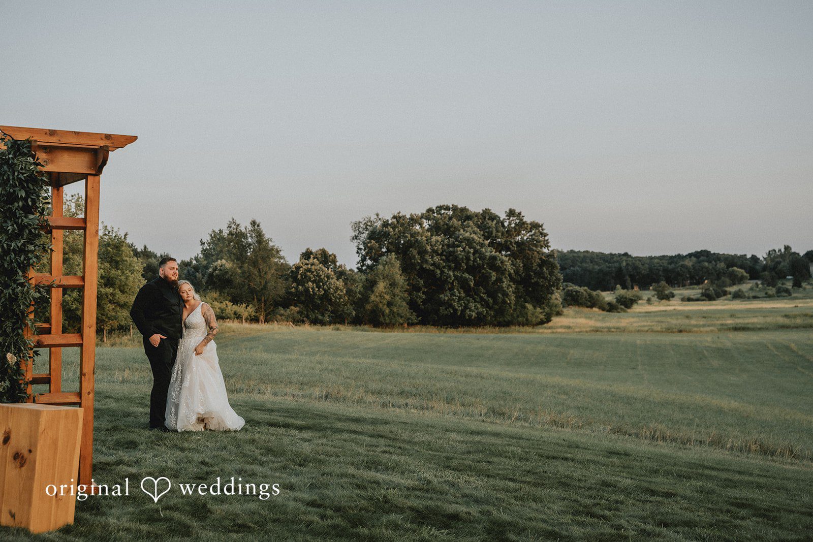 Samantha + Peyton Wide shot of newlyweds standing alone in grassy landscape.