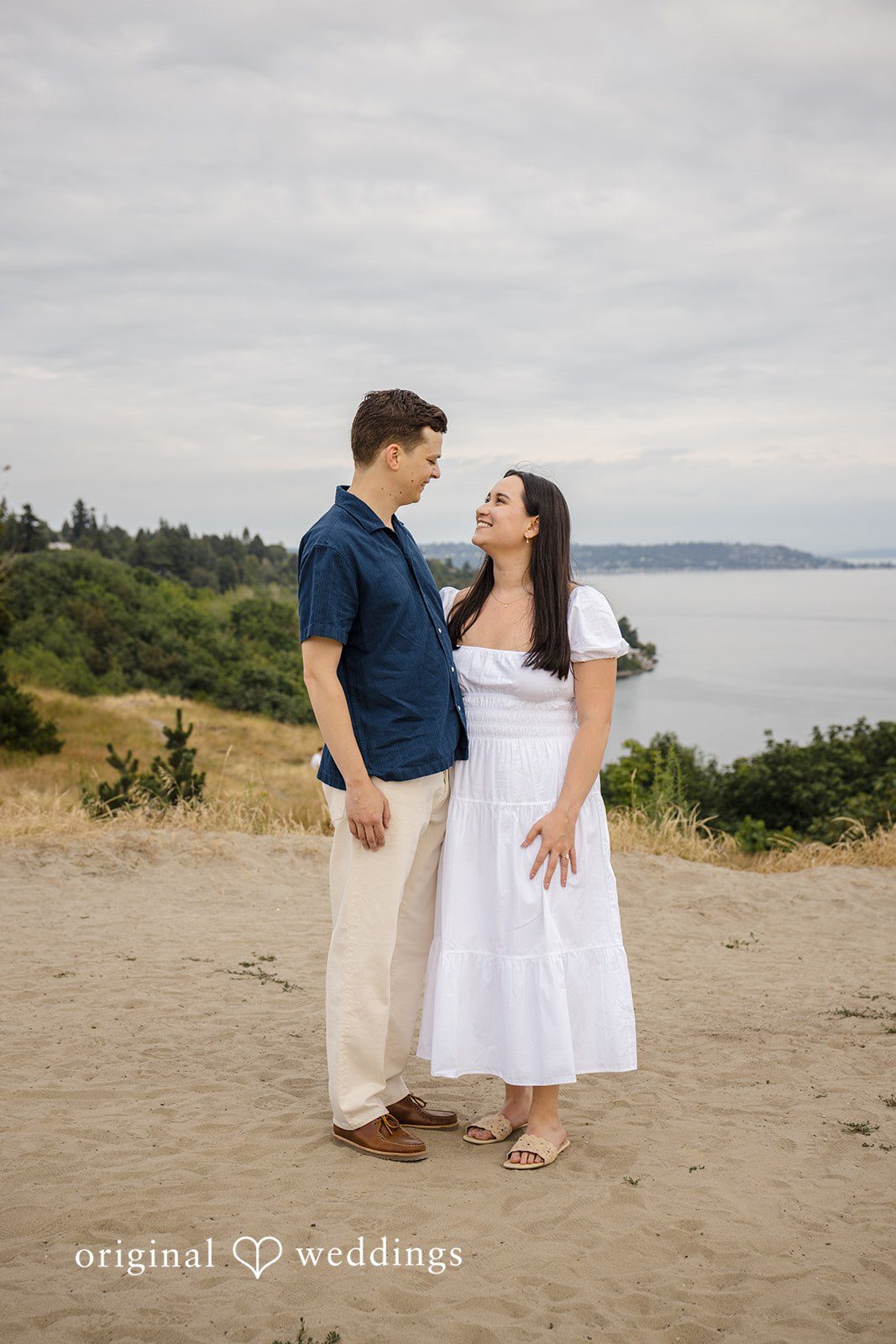 A couple standing together and holding hands on a grassy field.