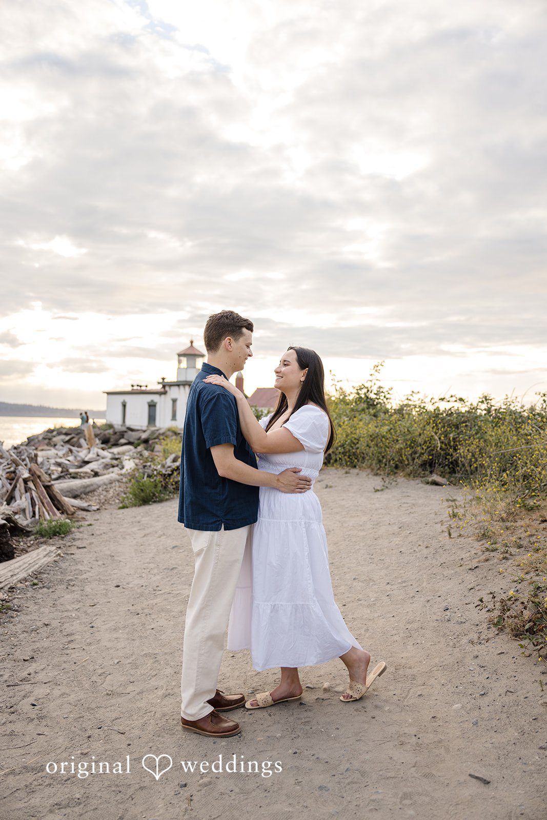 A couple holding hands and facing each other while walking along a scenic dirt path.