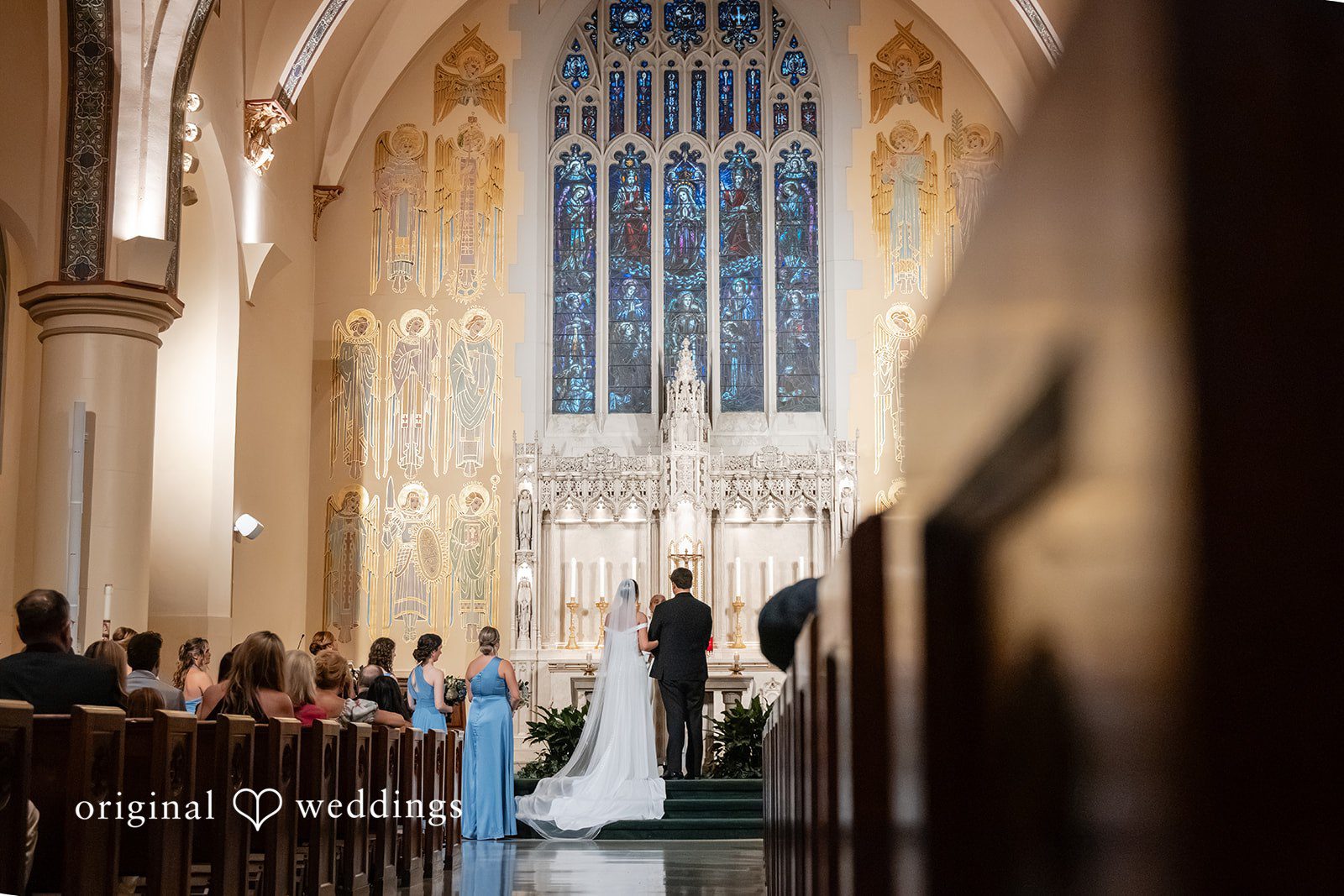 Mark + Caroline A long shot of the wedding ceremony viewed from the back of the church aisle.