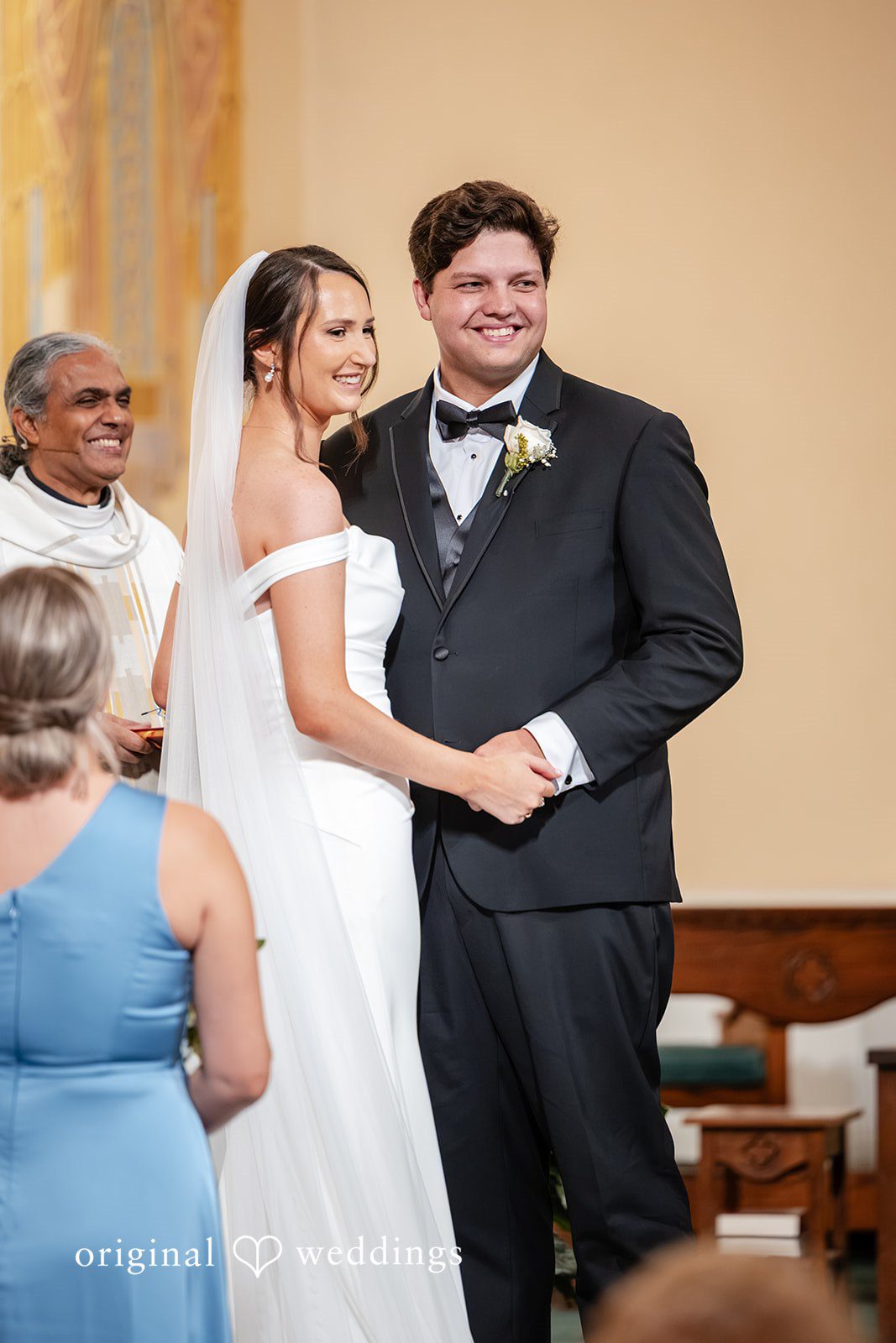 Mark + Caroline The newlyweds smiling and looking at each other at the altar after being married.