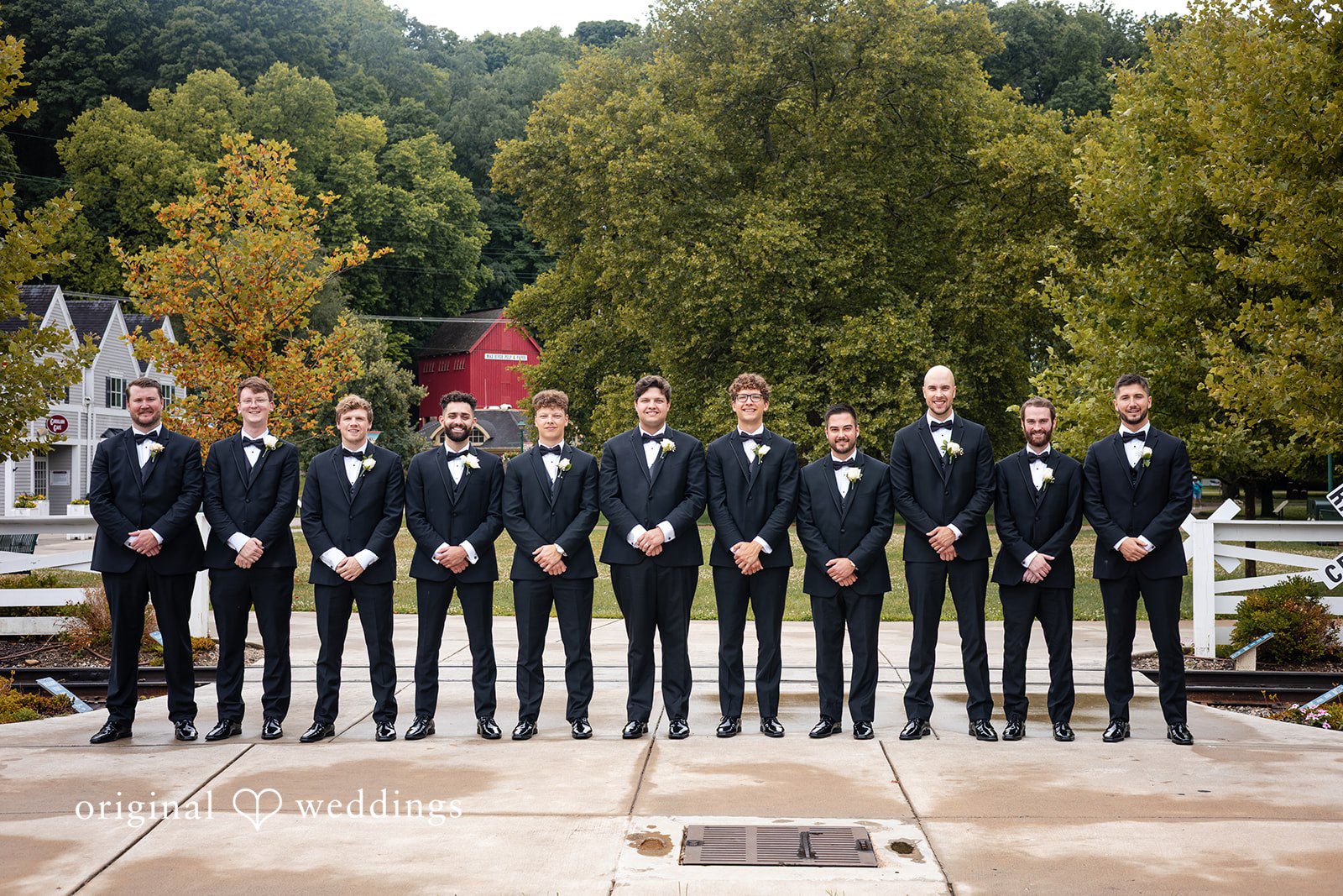 Mark + Caroline A groom posing with a line of groomsmen wearing matching dark suits.