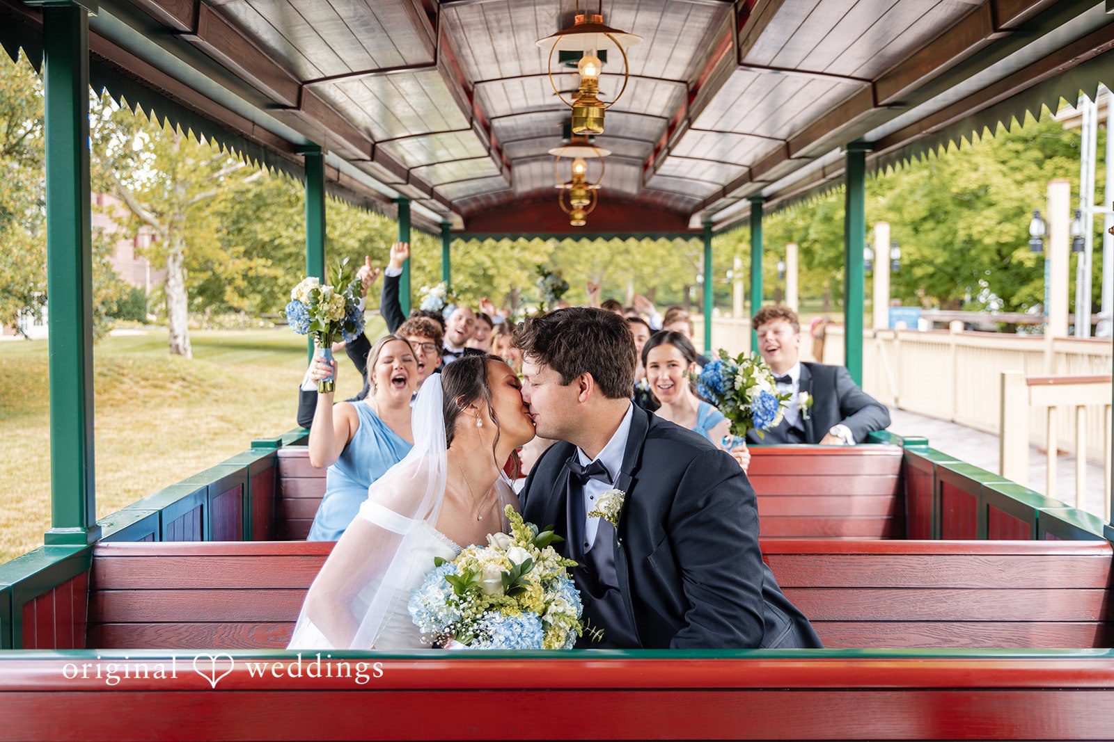 Mark + Caroline The bride and groom sharing a kiss while sitting together in an open-air trolley.