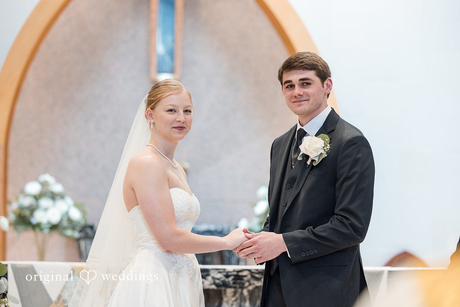Cora + Michael Cleveland Wedding Photographers capturing couple holding each other’s hand and standing while looking forward at the Emerald Event Center by Original Weddings