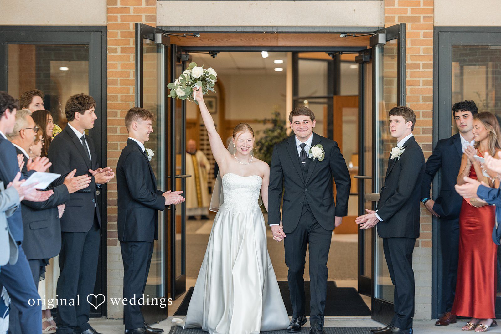 Cora + Michael Cleveland Wedding Photographers capturing couple coming outside and bride smiling with her hand up at the Emerald Event Center by Original Weddings
