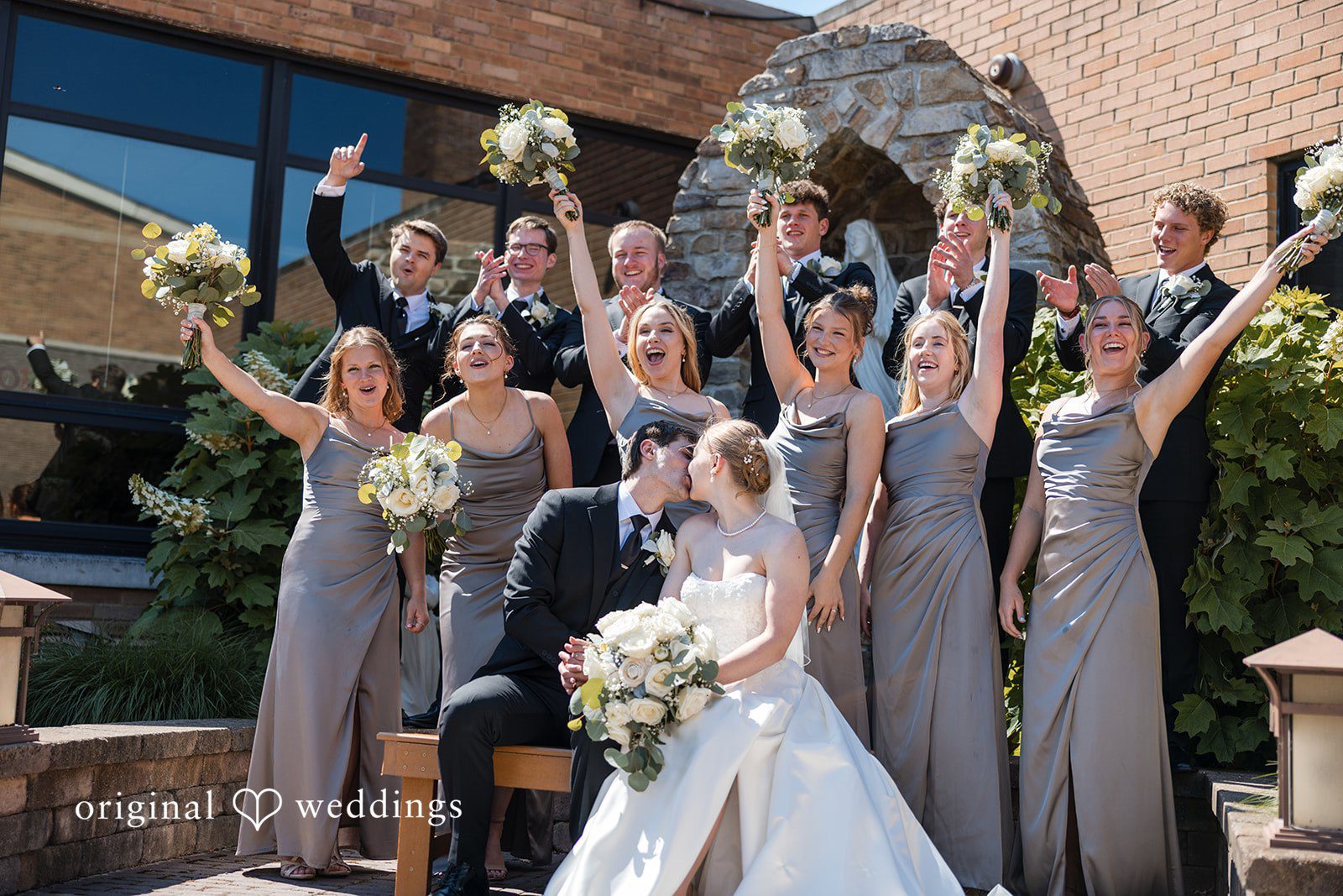 Cora + Michael Cleveland Wedding Photographers capturing couple kissing around bridesmaids and groomsmen at the Emerald Event Center by Original Weddings