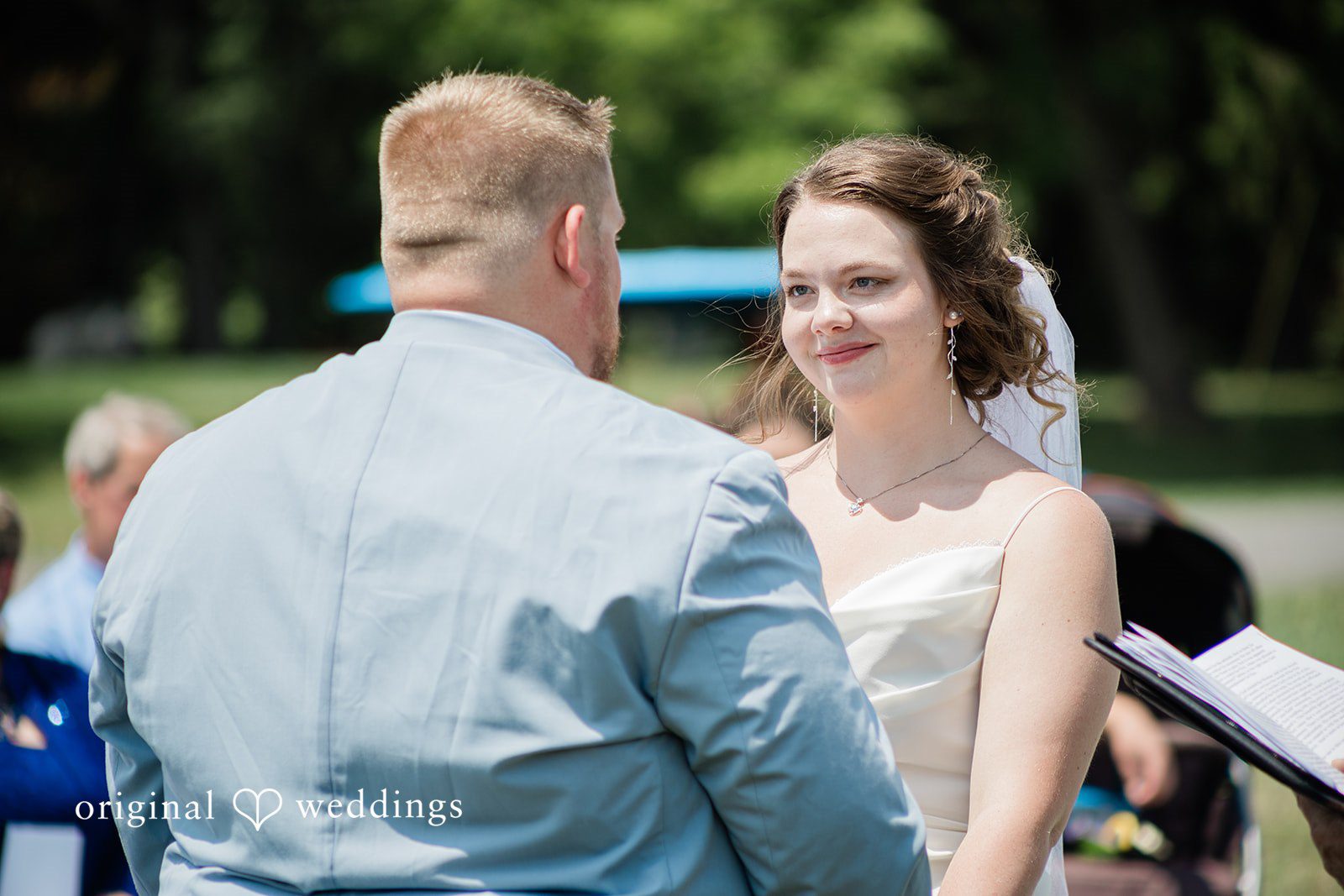 Michaela + Jake A groom in a blue suit looks toward his bride at the altar.