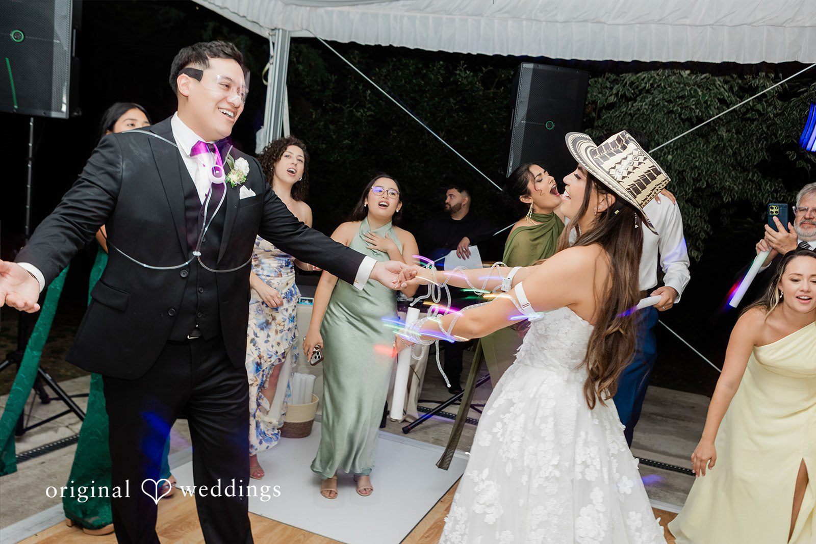 Groom dancing energetically with wedding guests on a dance floor.