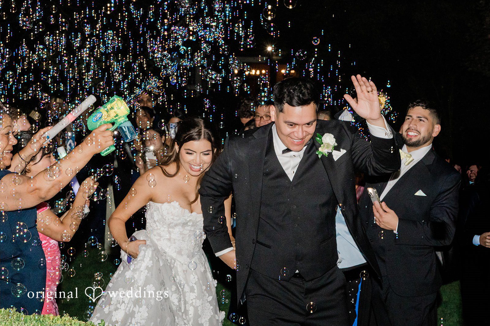 Bride and groom walking through a crowd of cheering guests during their grand exit.