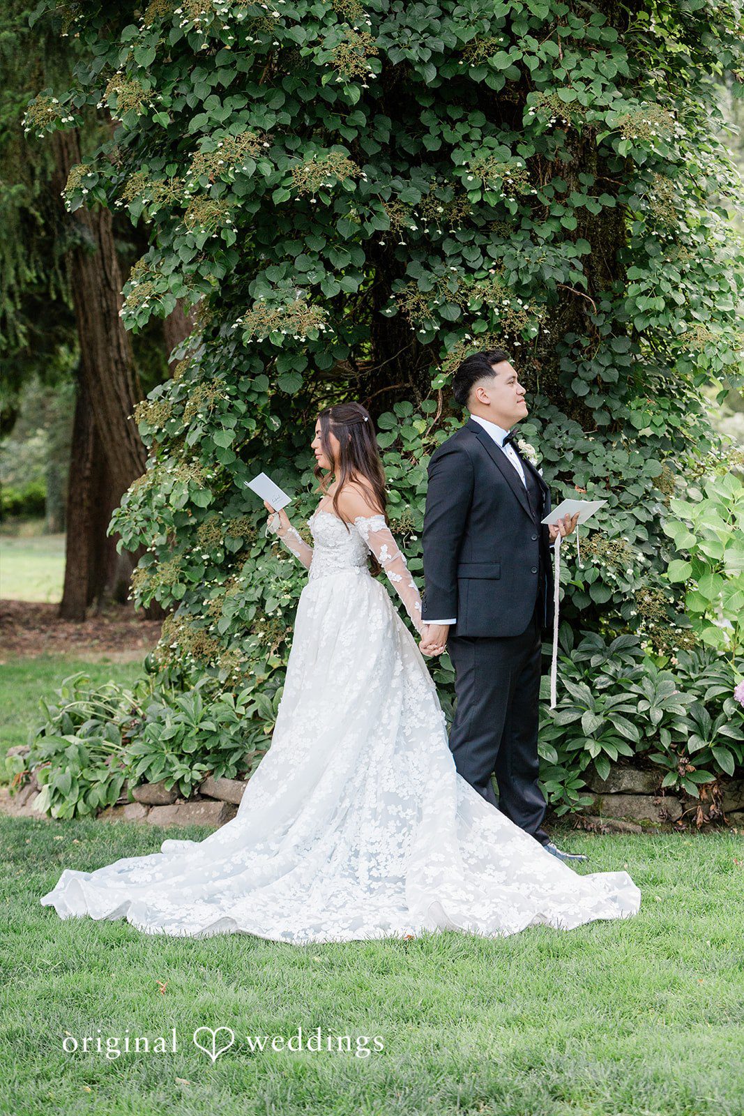 Bride and groom posing together on a grassy lawn.
