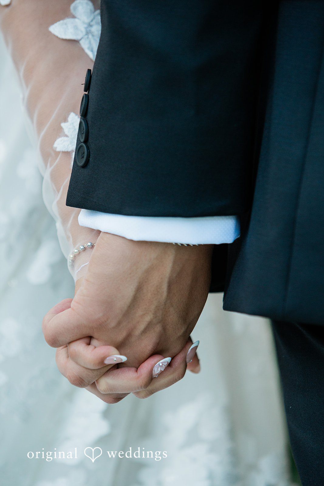 Close-up of two individuals holding hands, showing a suit sleeve.