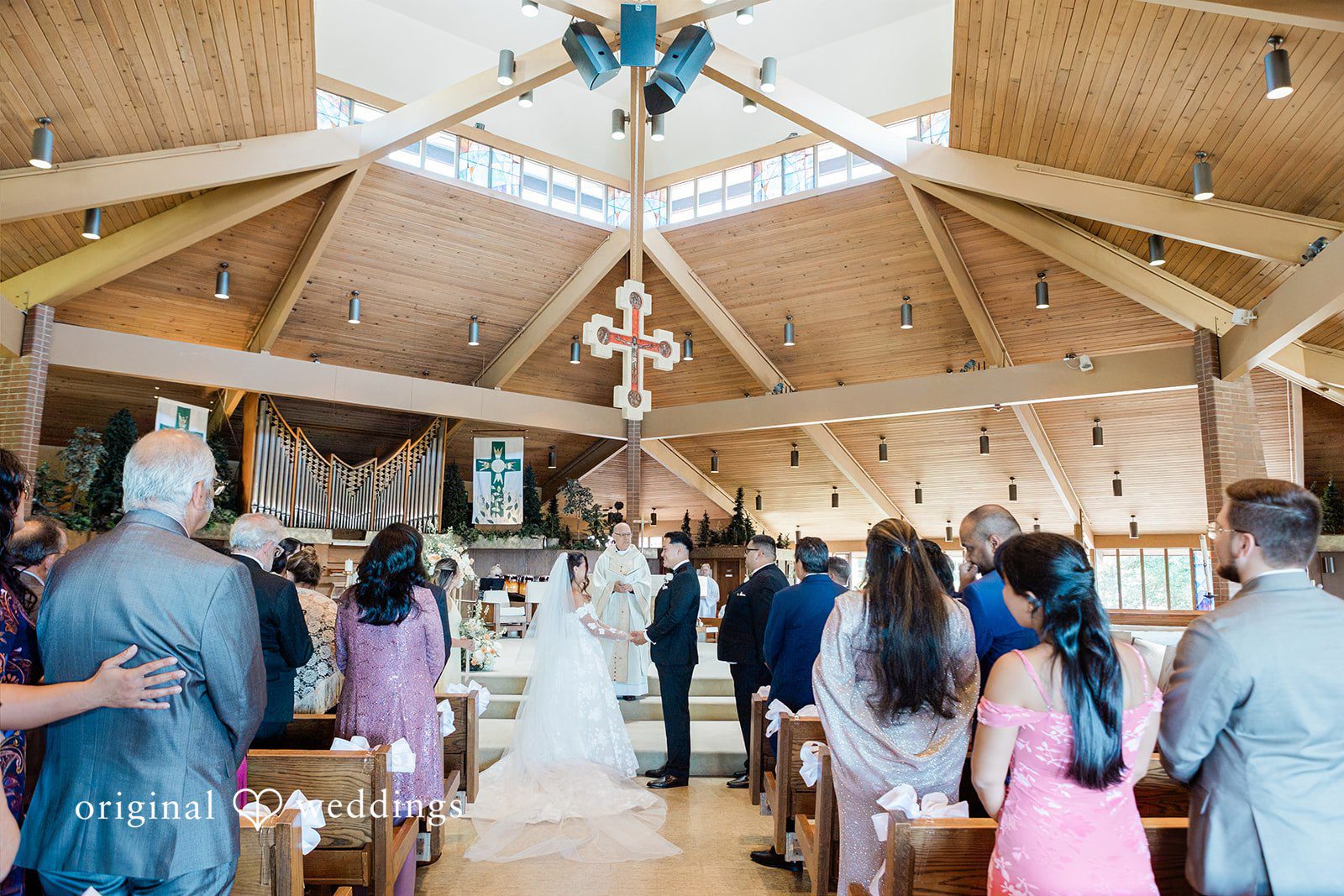 Wedding guests seated in wooden pews watching a church ceremony.