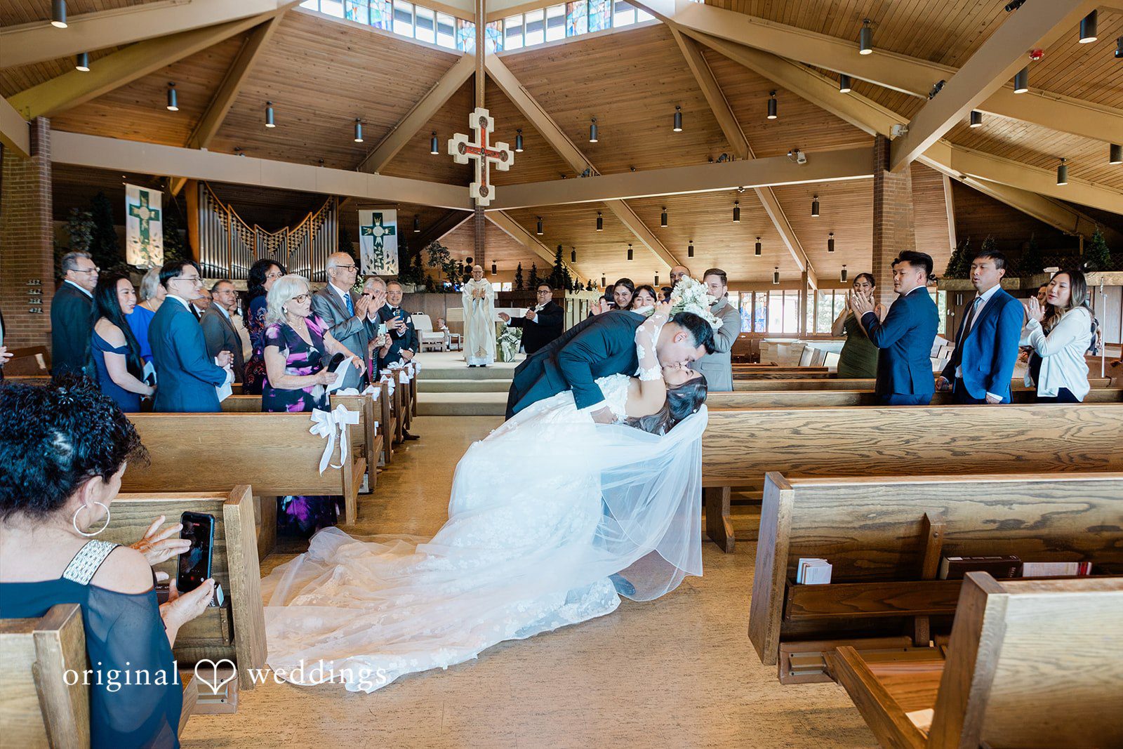 Newlyweds walking through the chapel pews surrounded by guests.