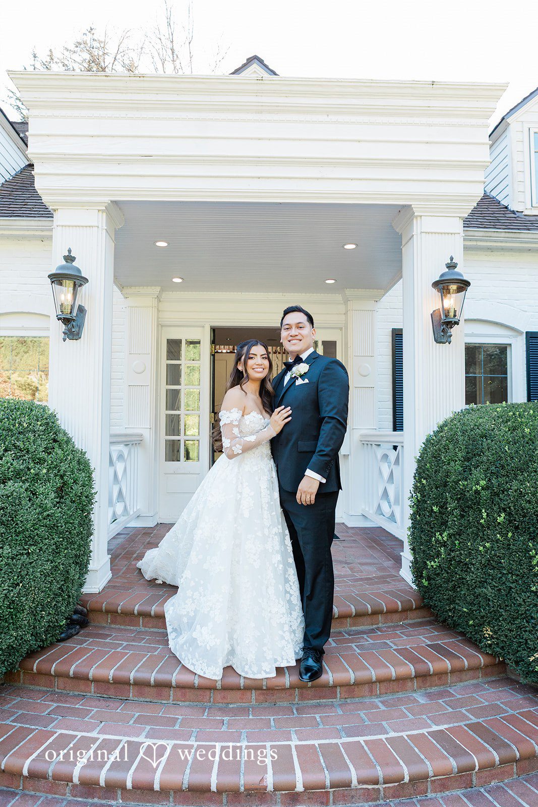 Bride and groom posing on the stone steps of a building.