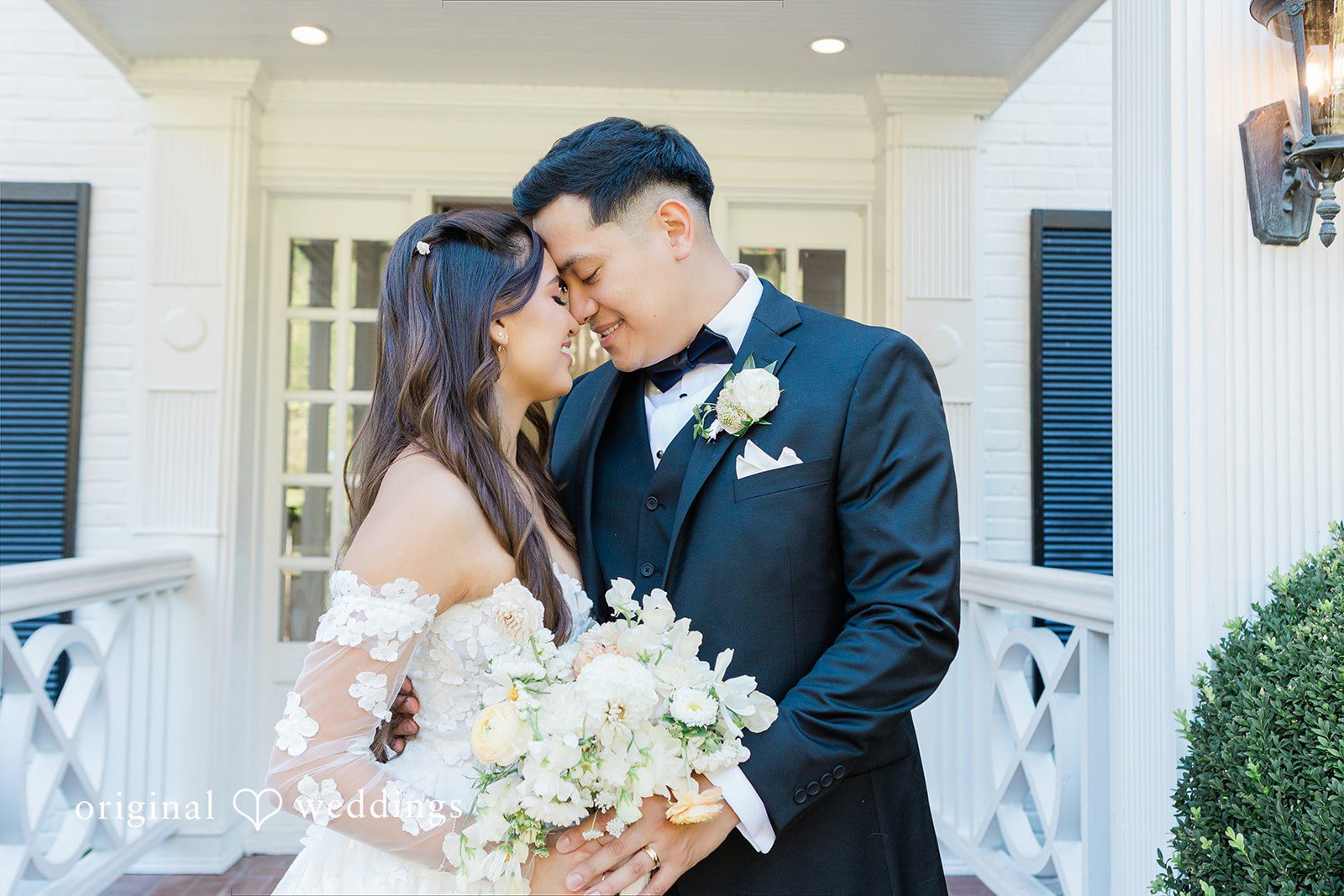 Groom leaning close to the bride as she holds flowers.