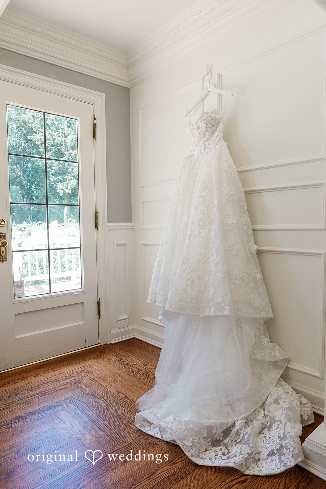 White wedding gown hanging elegantly near a window.