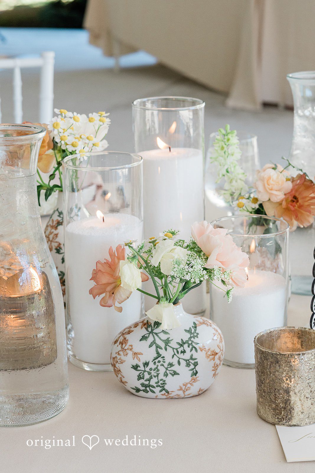 Wedding table centerpiece with burning candles and delicate white flowers.