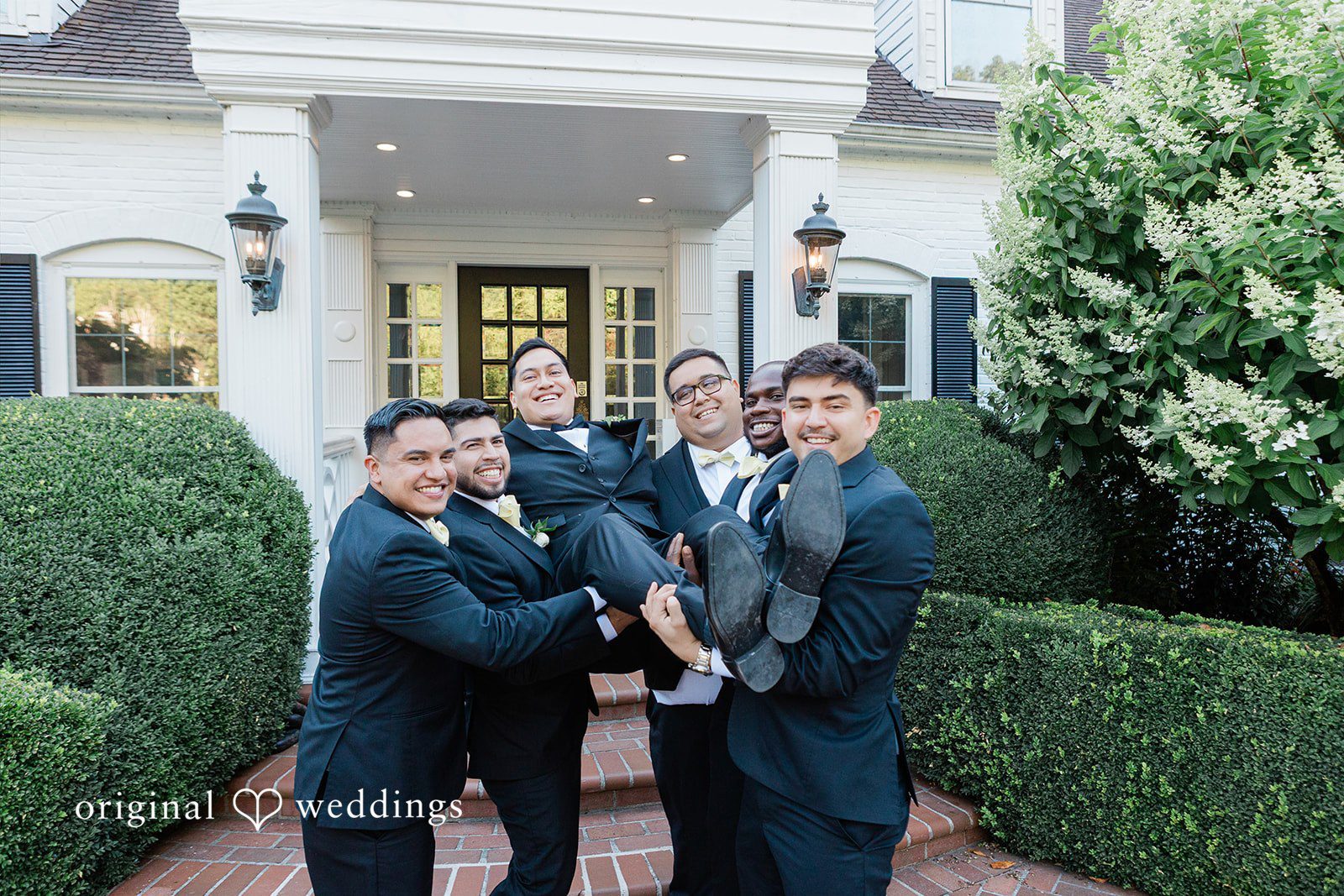 Group of groomsmen playfully lifting up the groom.