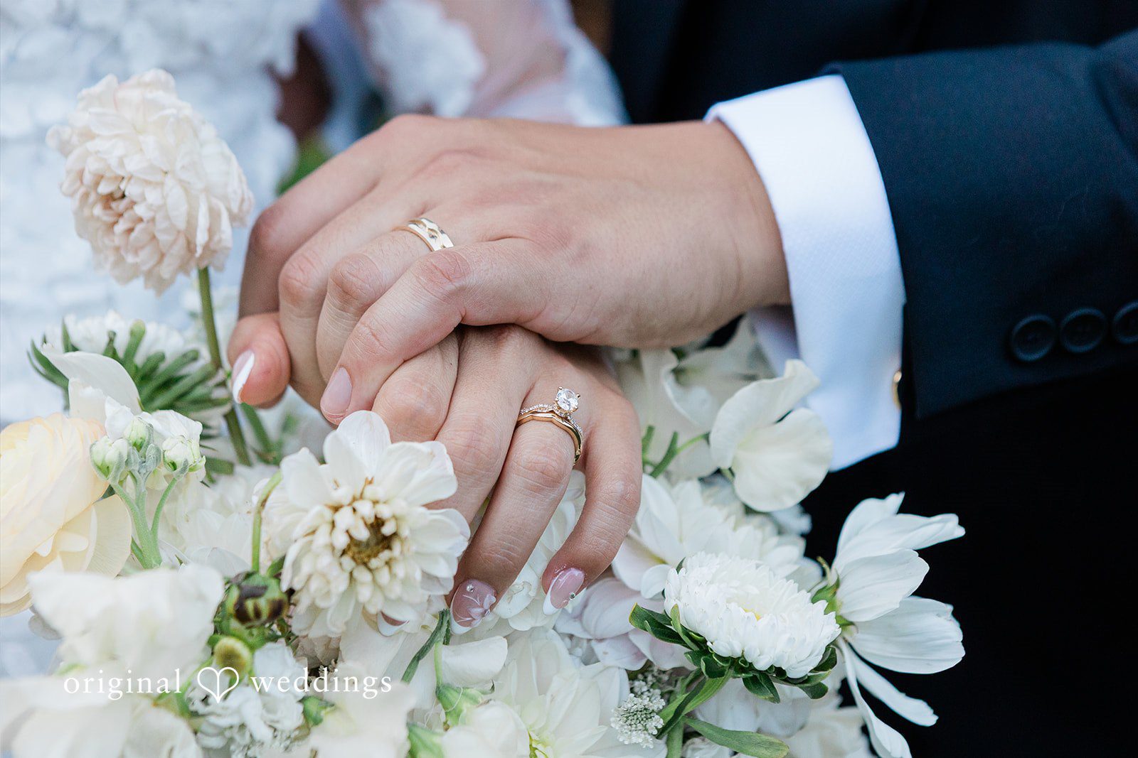 Close-up of a hand with a wedding rings resting on a bouquet.