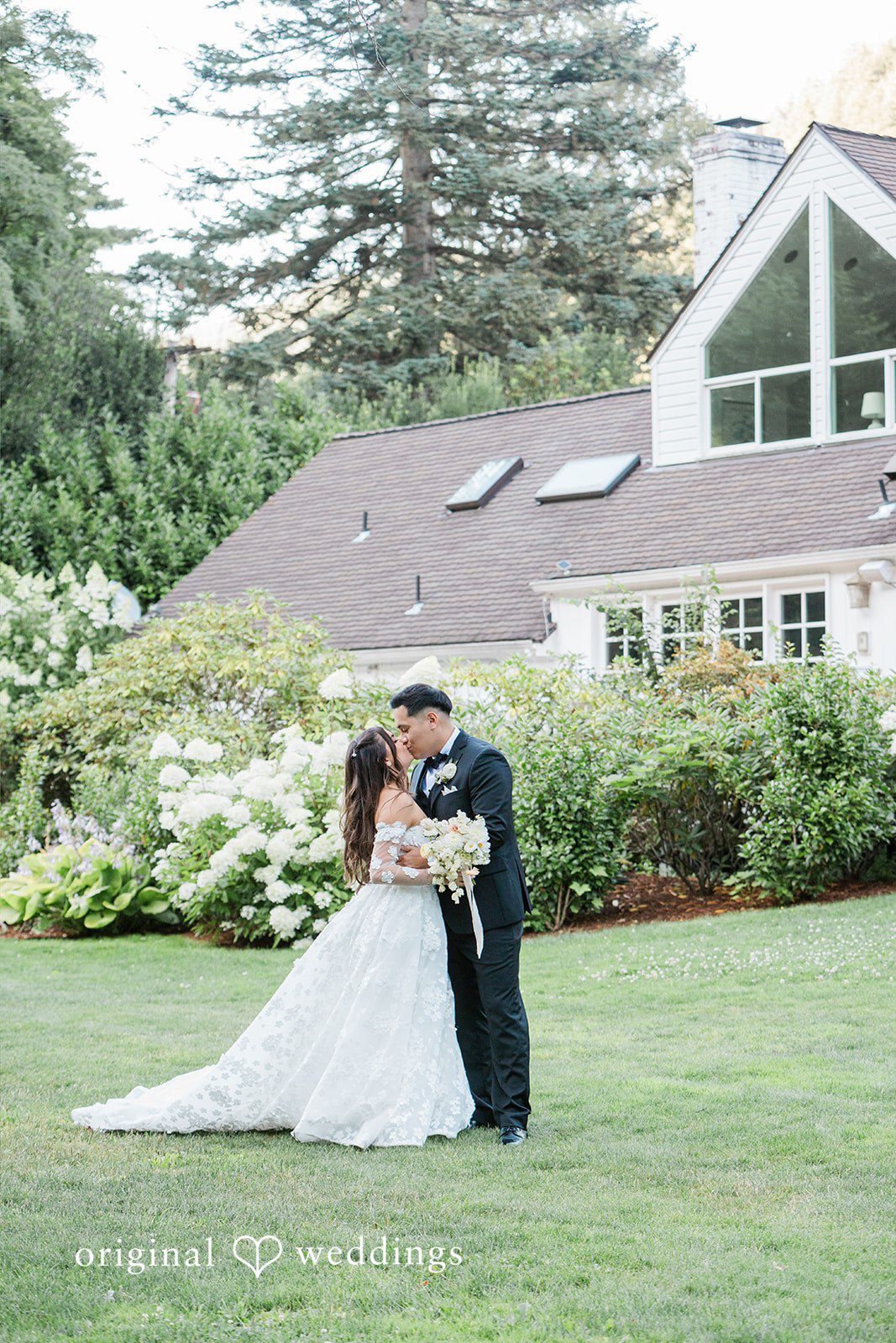 Bride and groom leaning in for a kiss on a green lawn.