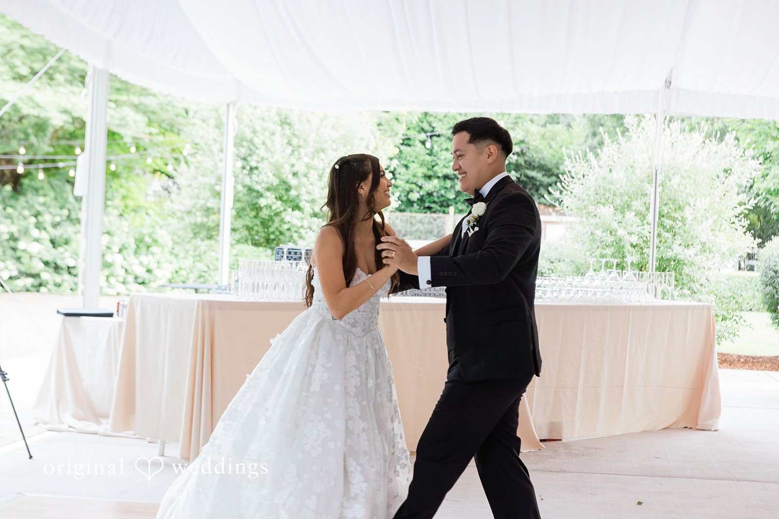 Bride and groom sharing their first dance under a white canopy.