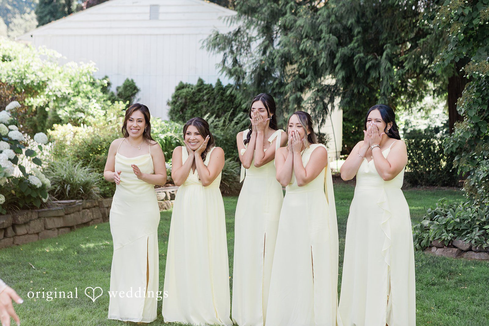Five bridesmaids wearing matching long, light-colored gowns.