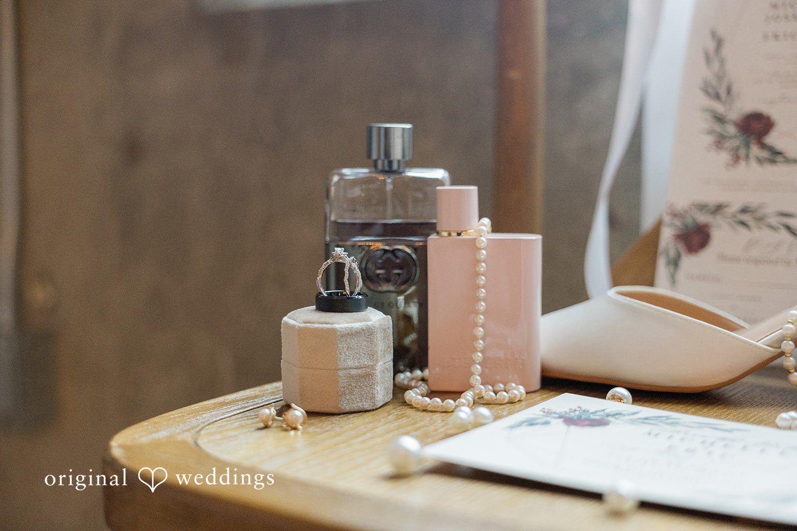 Michelle + Eric A wedding perfume bottle, bridal shoes, and invitations displayed on a surface.