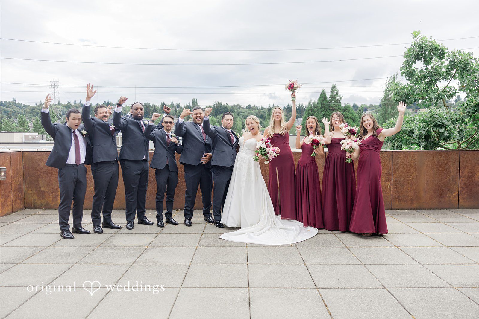 Michelle + Eric A full wedding party with groomsmen throwing their hands up and bridesmaids posing on a balcony.