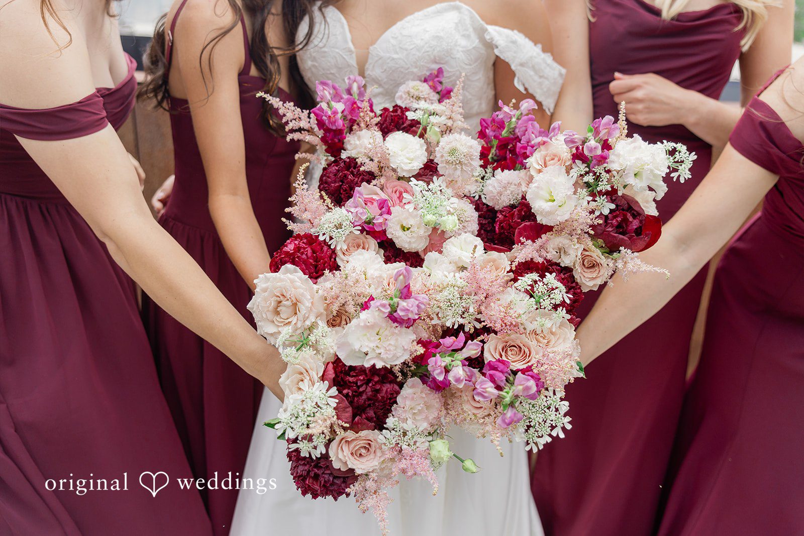 Michelle + Eric A close-up of bridesmaids in burgundy dresses holding large floral bouquets.