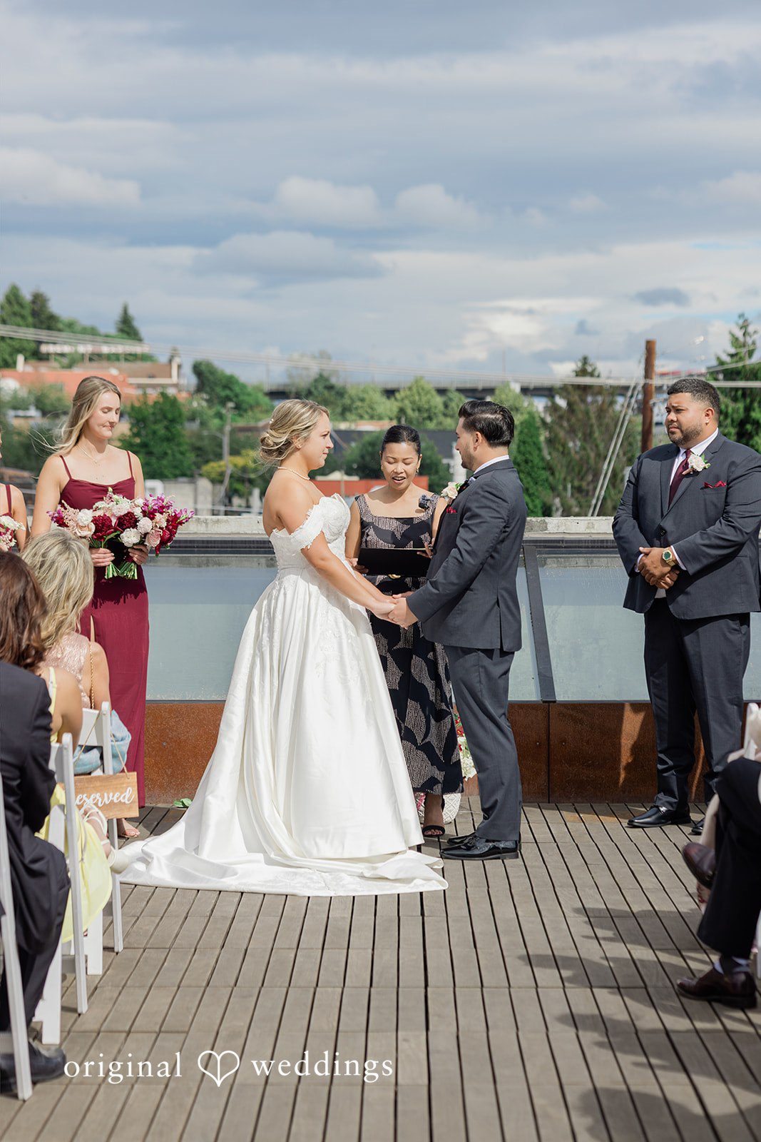 Michelle + Eric A bride and groom holding hands during their wedding ceremony on a wooden deck.