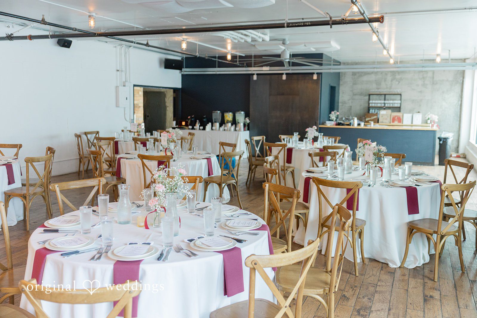 Michelle + Eric A wedding reception hall decorated with round tables and white floral centerpieces.