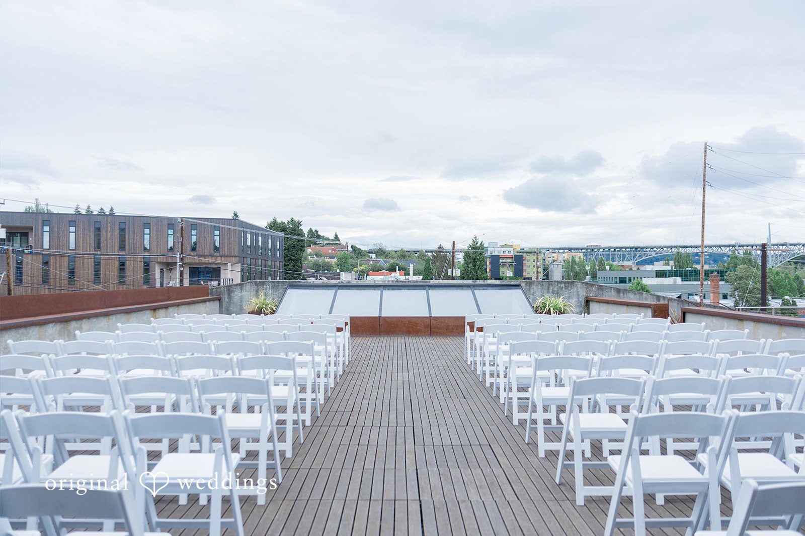 Michelle + Eric An empty rooftop wedding ceremony venue set up with white chairs.