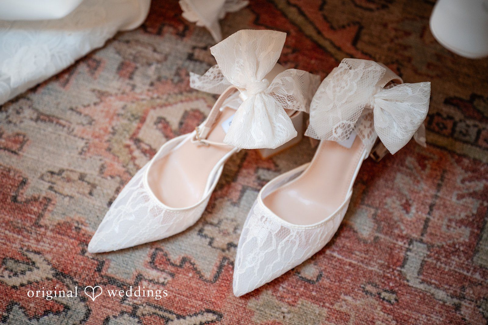 Emilia + Charlie A pair of white bridal heels with large bows resting on steps.