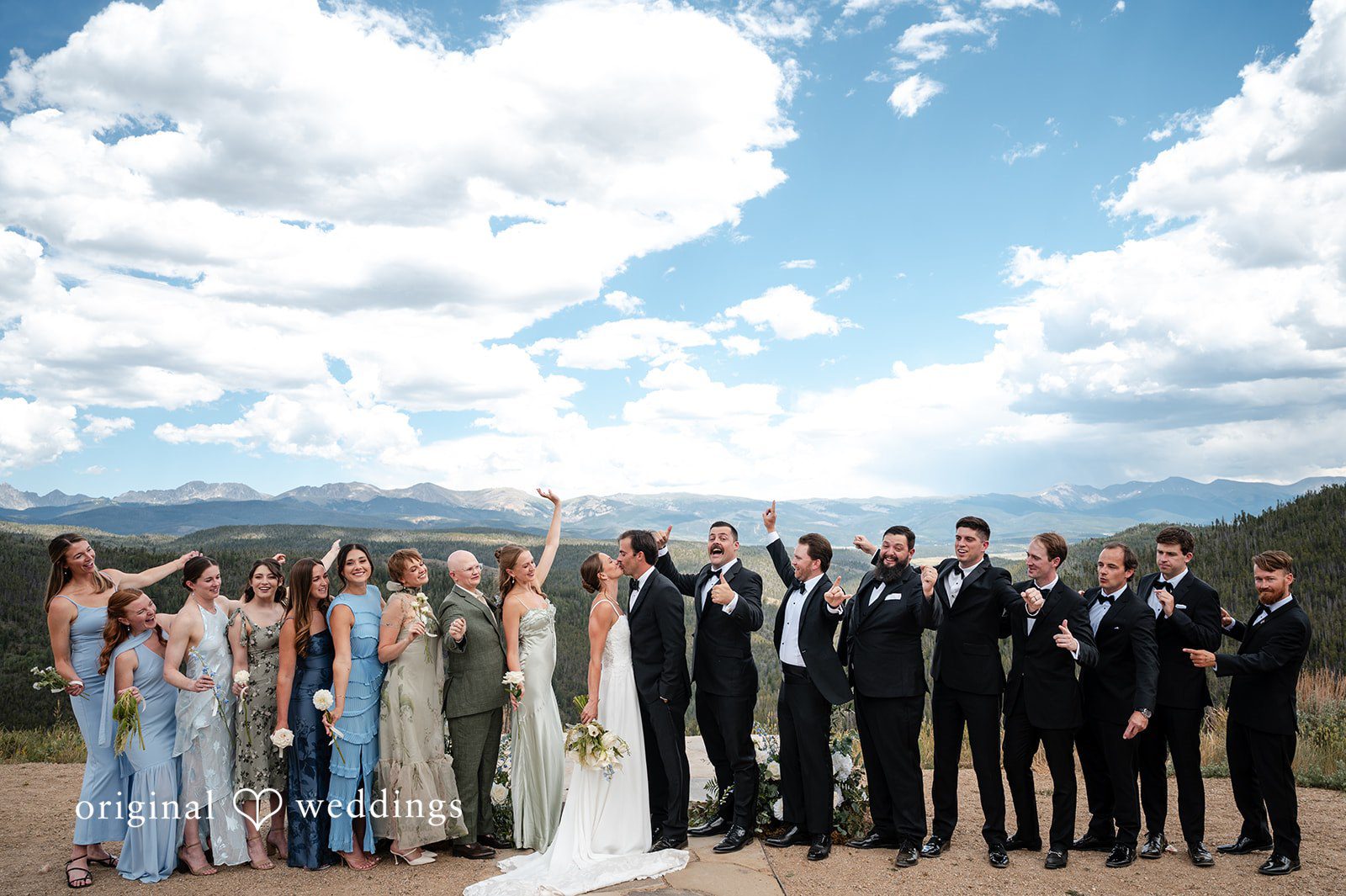 Emilia + Charlie A large wedding party posing together against a backdrop of distant mountains.