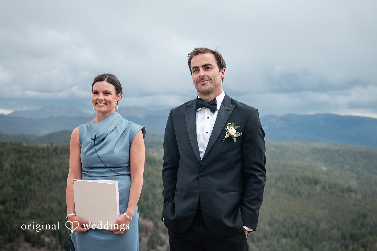 Emilia + Charlie A woman in a blue dress standing next to a man in a tuxedo.