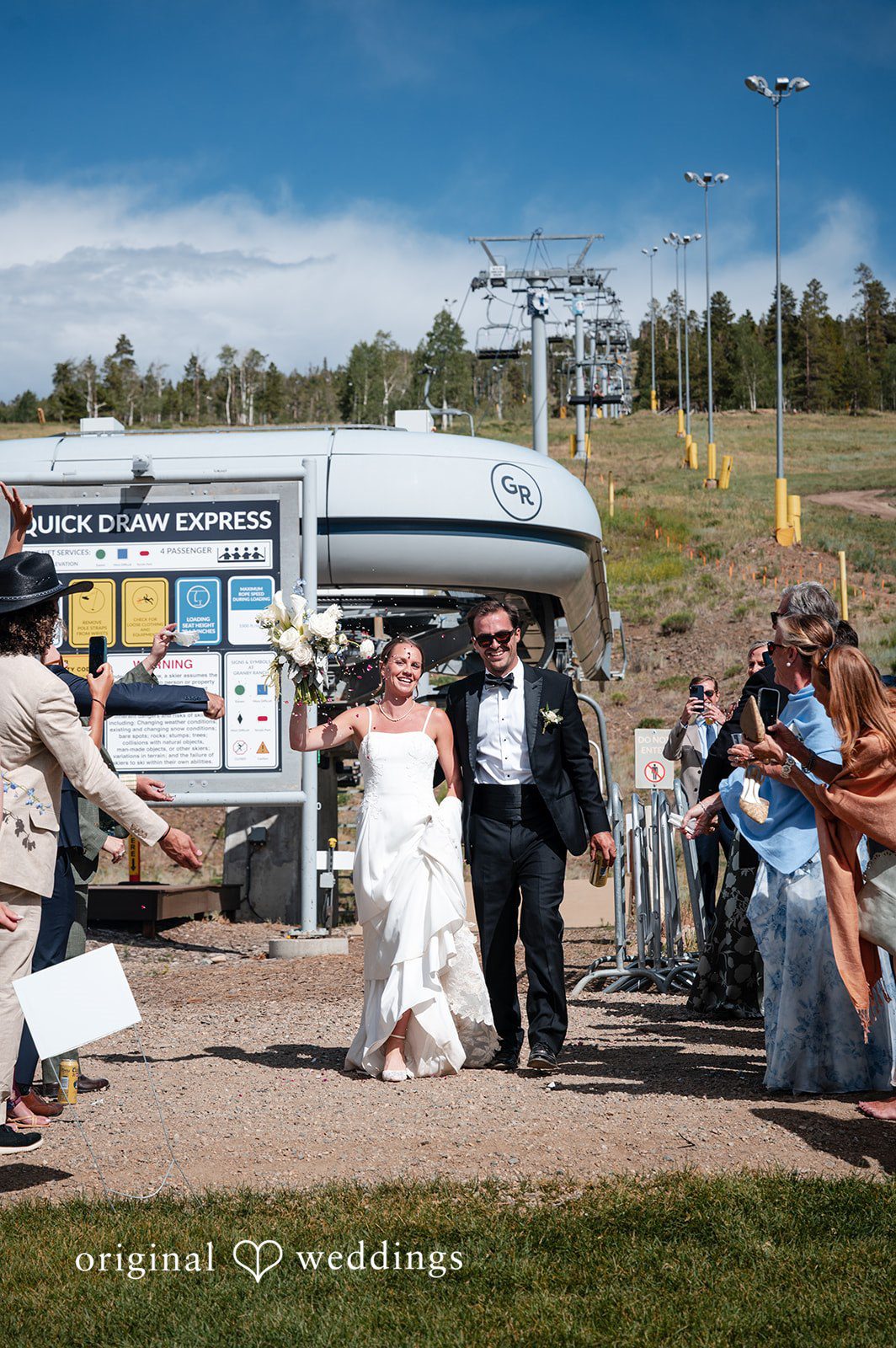 Emilia + Charlie A bride and groom walking down a path while guests toss flower petals.