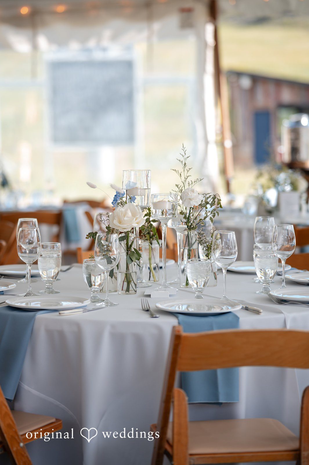 Emilia + Charlie Elegantly set round reception tables with glassware and flowers.