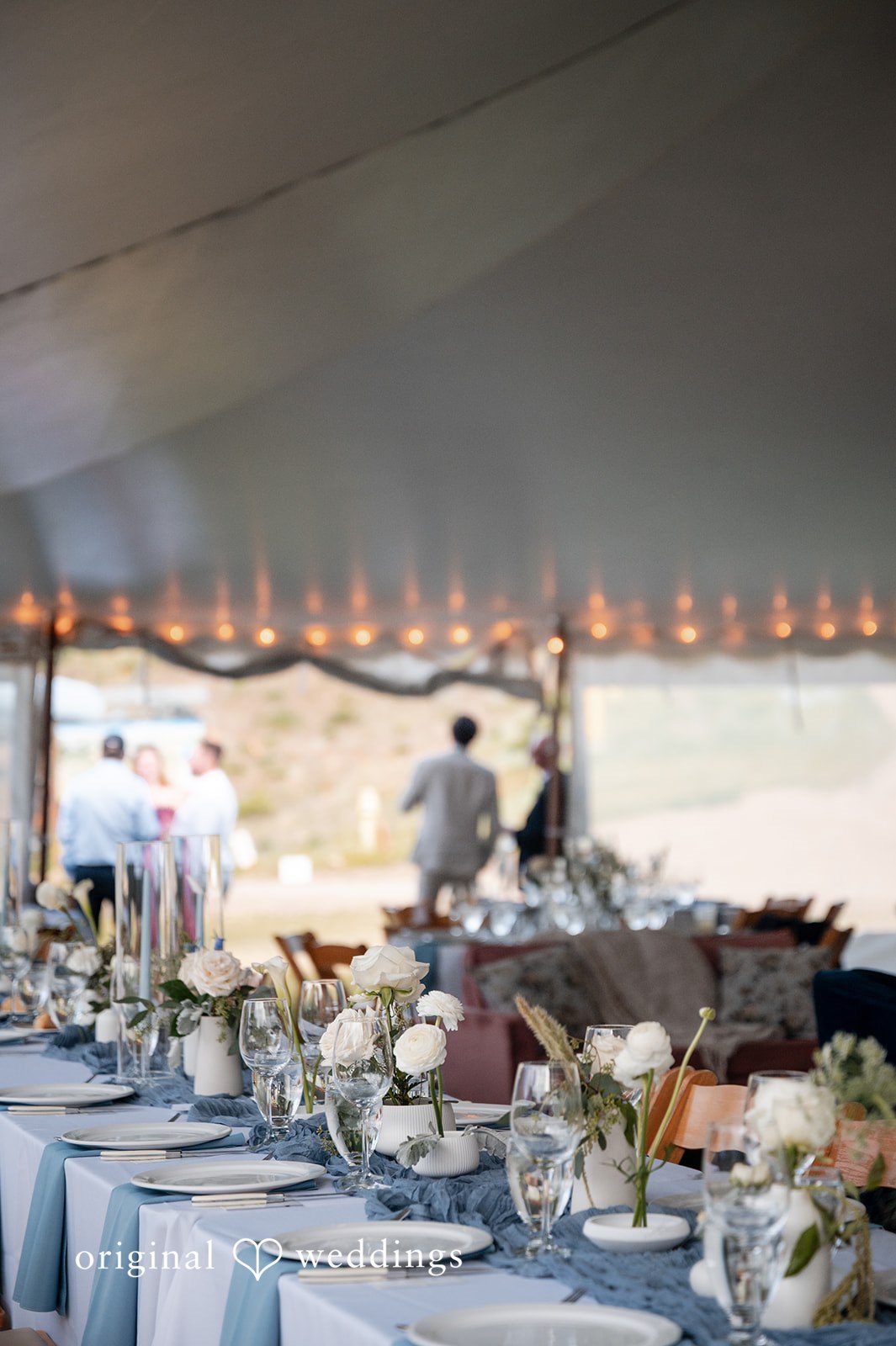 Emilia + Charlie Decorated dining tables with floral centerpieces inside a white event tent.