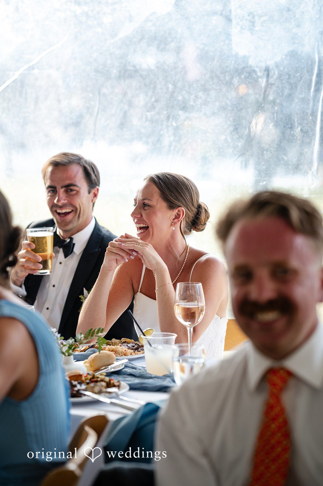 Emilia + Charlie A groom and wedding guests reacting and laughing during a reception.