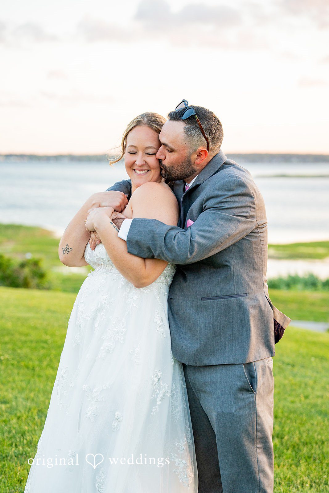 Alex + Courtney A groom wrapping his arms around a smiling bride from behind.