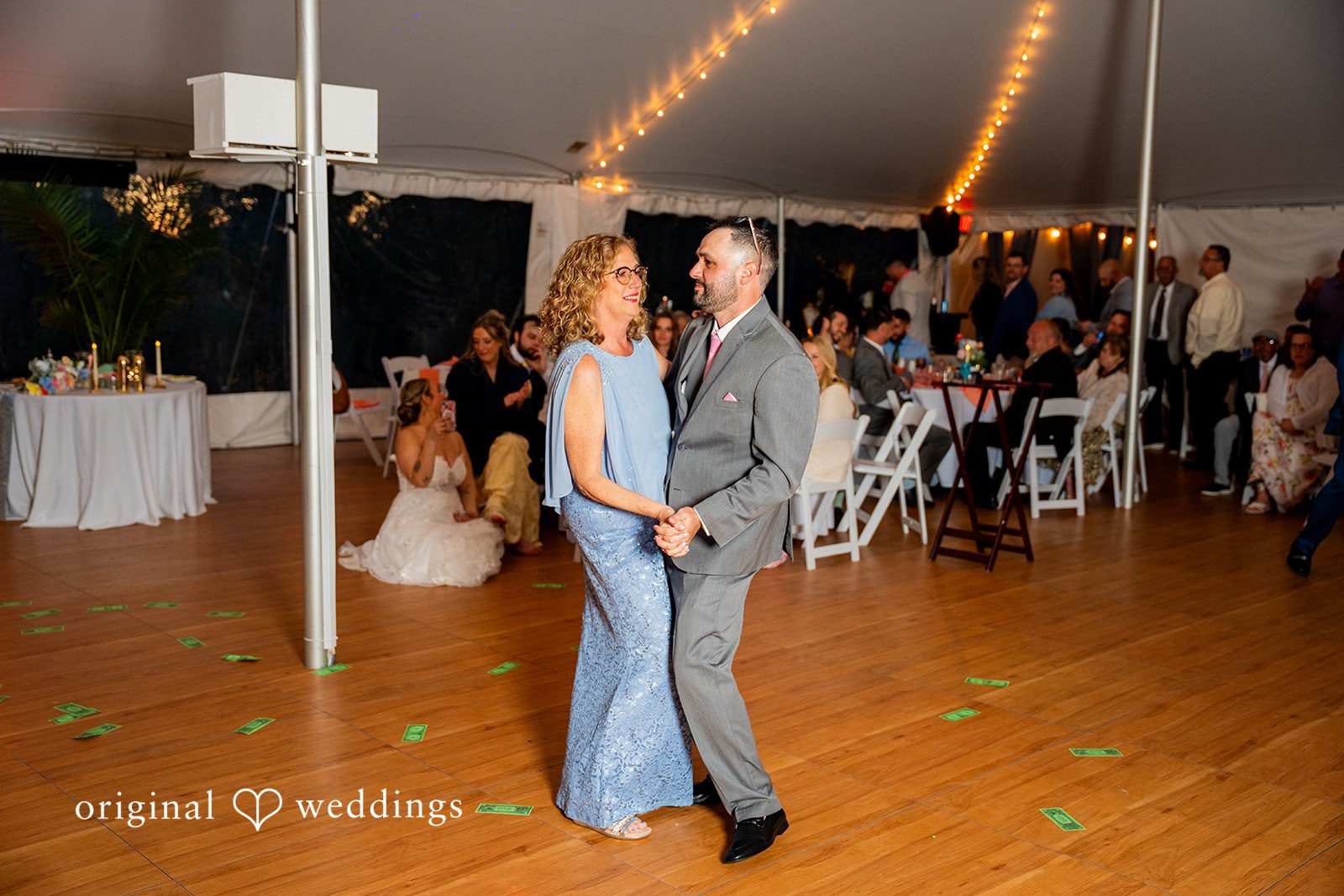 Alex + Courtney A women and groom slow dancing under reception tent lighting.