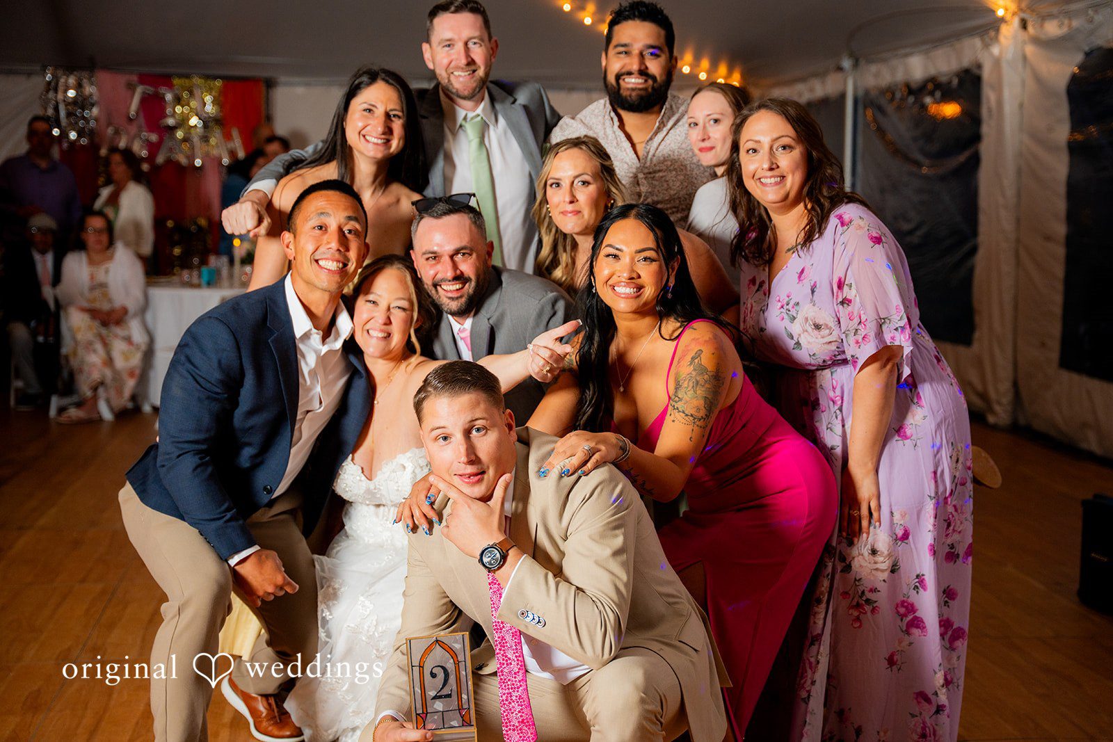 Alex + Courtney A large, energetic group of wedding guests posing closely together.