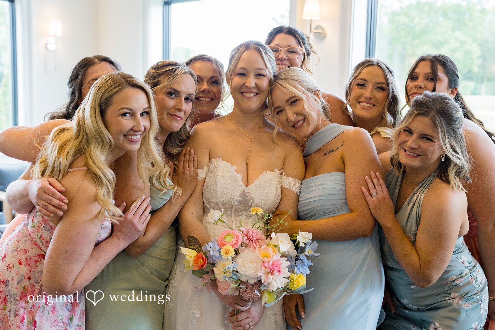Alex + Courtney A group of bridesmaids smiling together in light blue dresses.