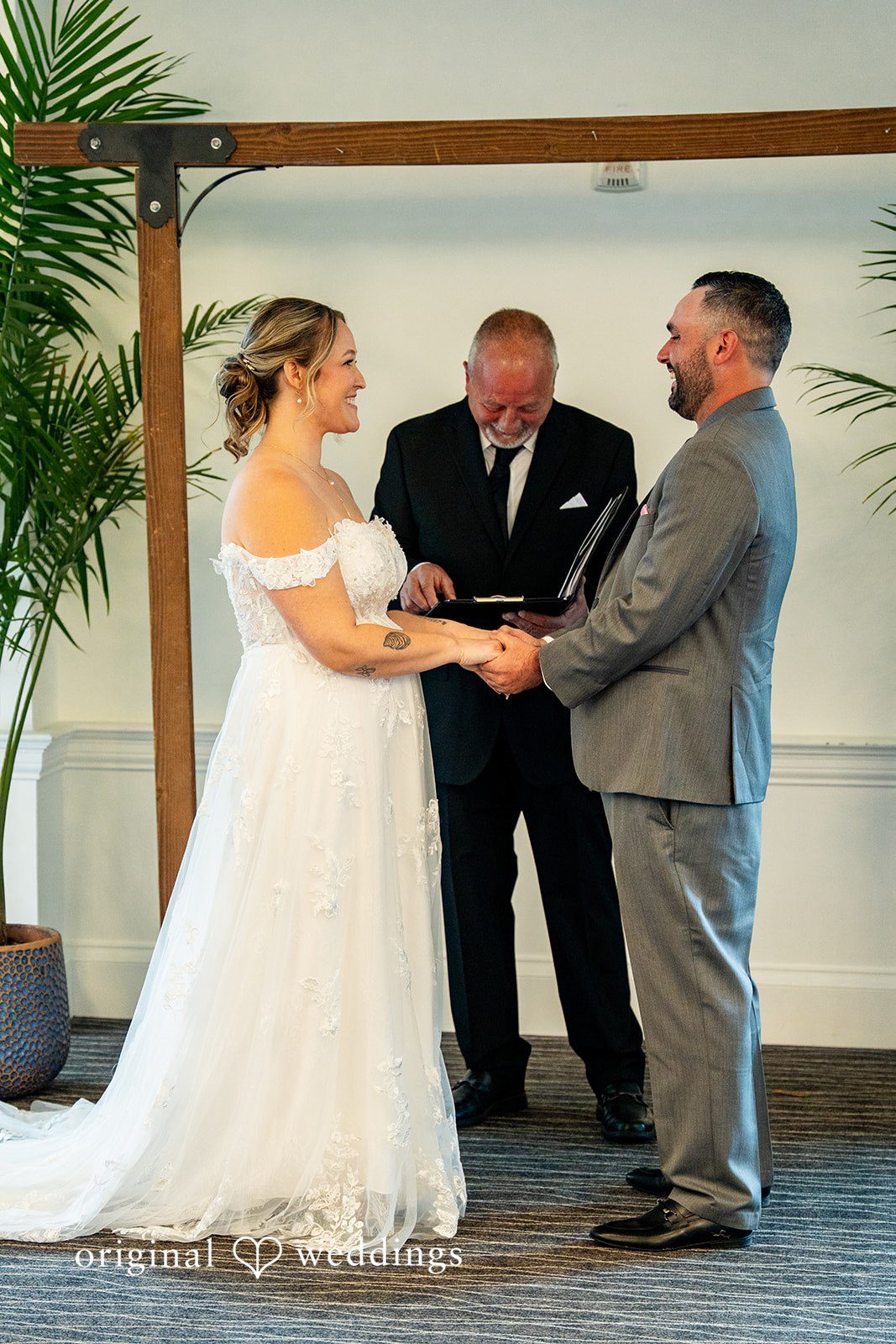 Alex + Courtney An officiant speaking to a bride and groom holding hands.